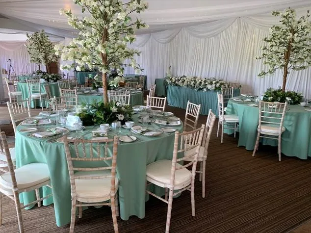 Wedding reception in kent with a layout with green chair sashes and wall draping and centre pieces
