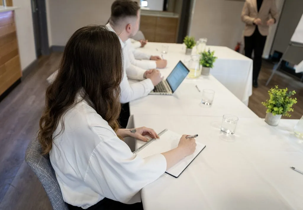 Meeting delegates sitting at table with laptops listening to the speaker at a corporate space in dartford