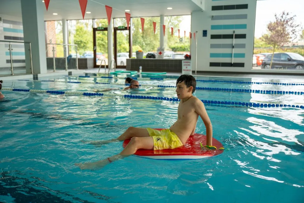 Boy sitting on float in the pool for family swim time in dartford