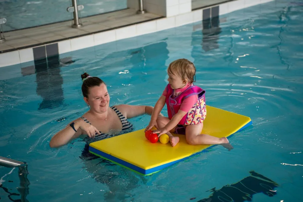 Woman and child on float having fun in swimming pool in swanley