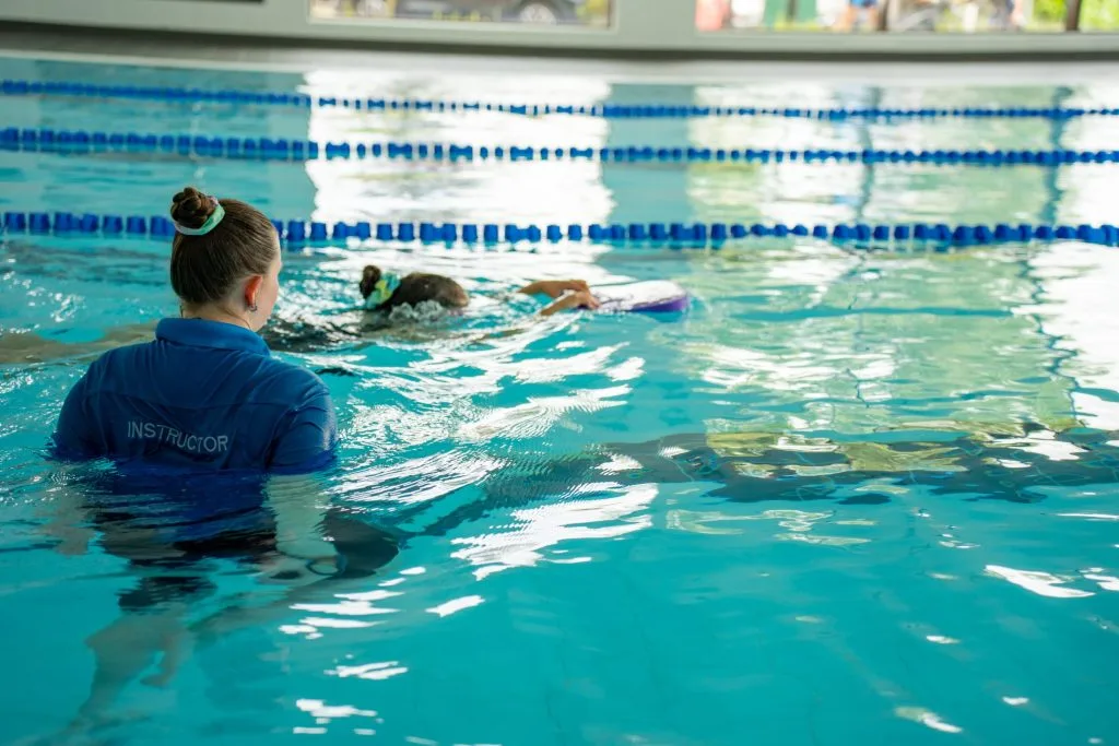 Woman giving a child a swimming lesson in pool in swanley