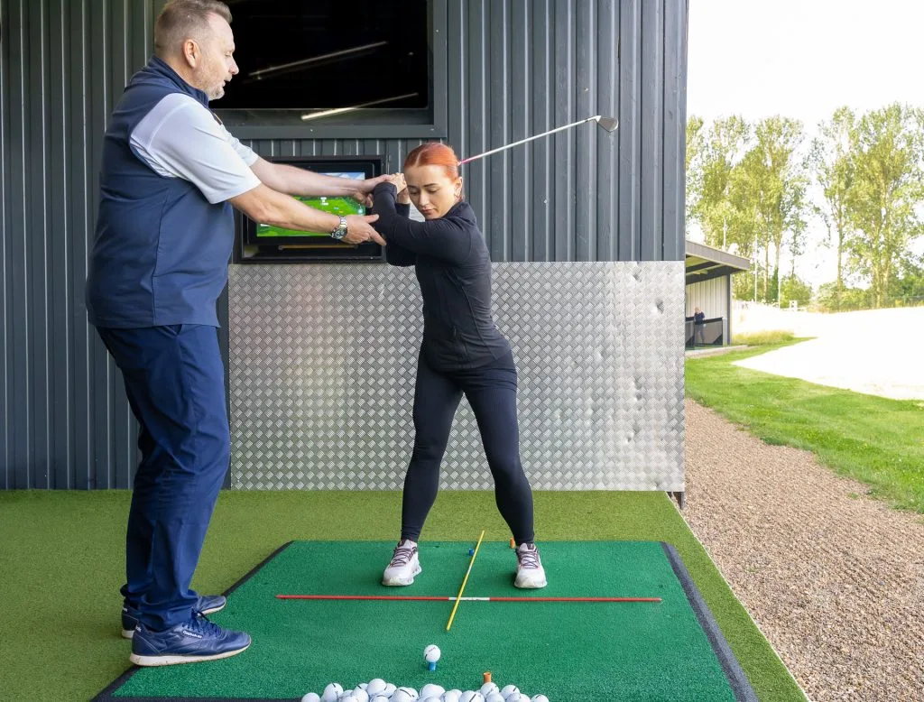 golfer in backswing getting a lesson in kent by a proffesional