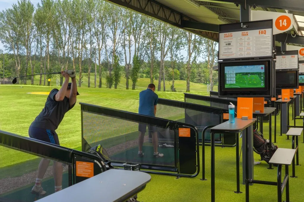 Range bays showing the trackman technology and man swinging